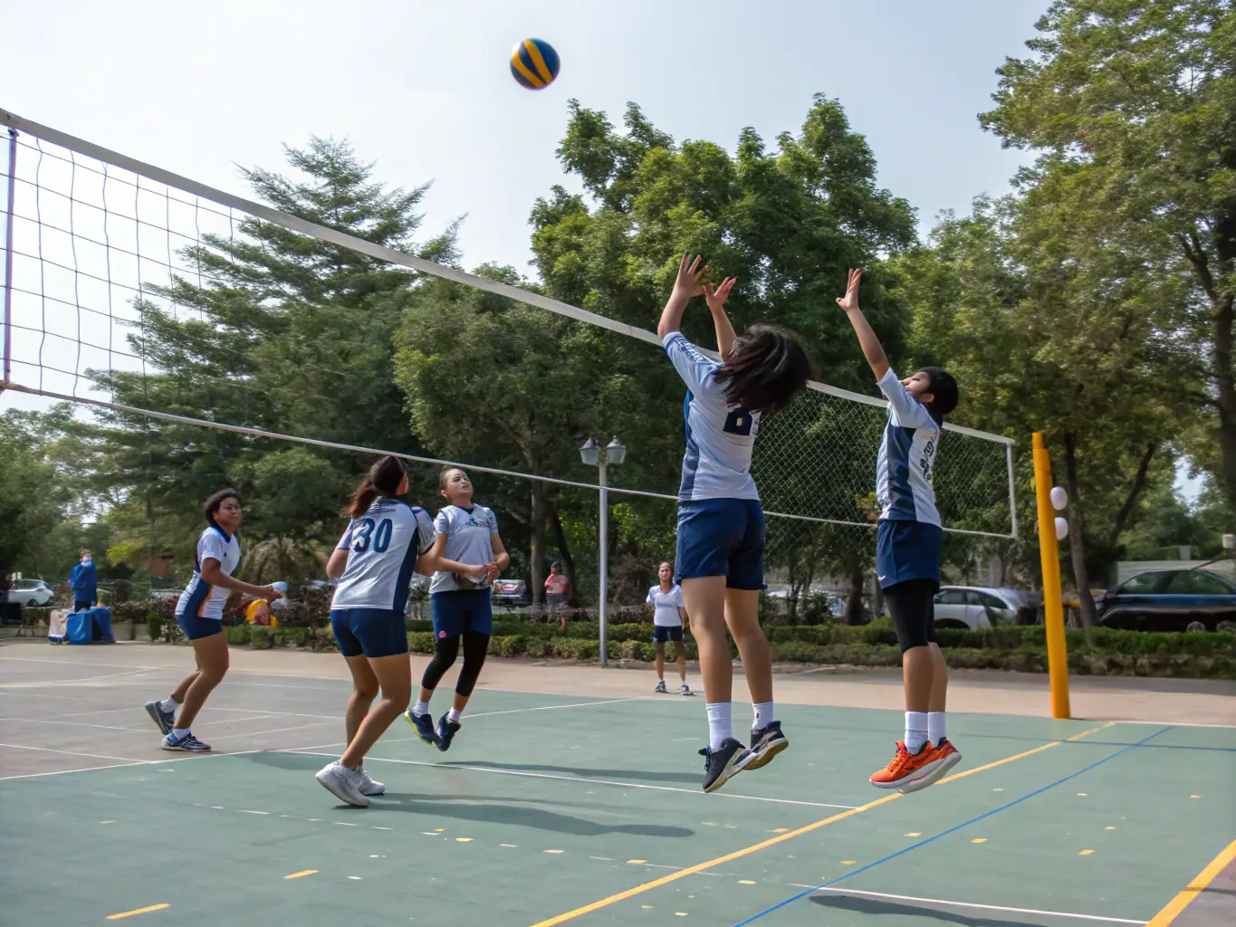 A group of students engaged in a volleyball match, showing coordination and enthusiasm.
